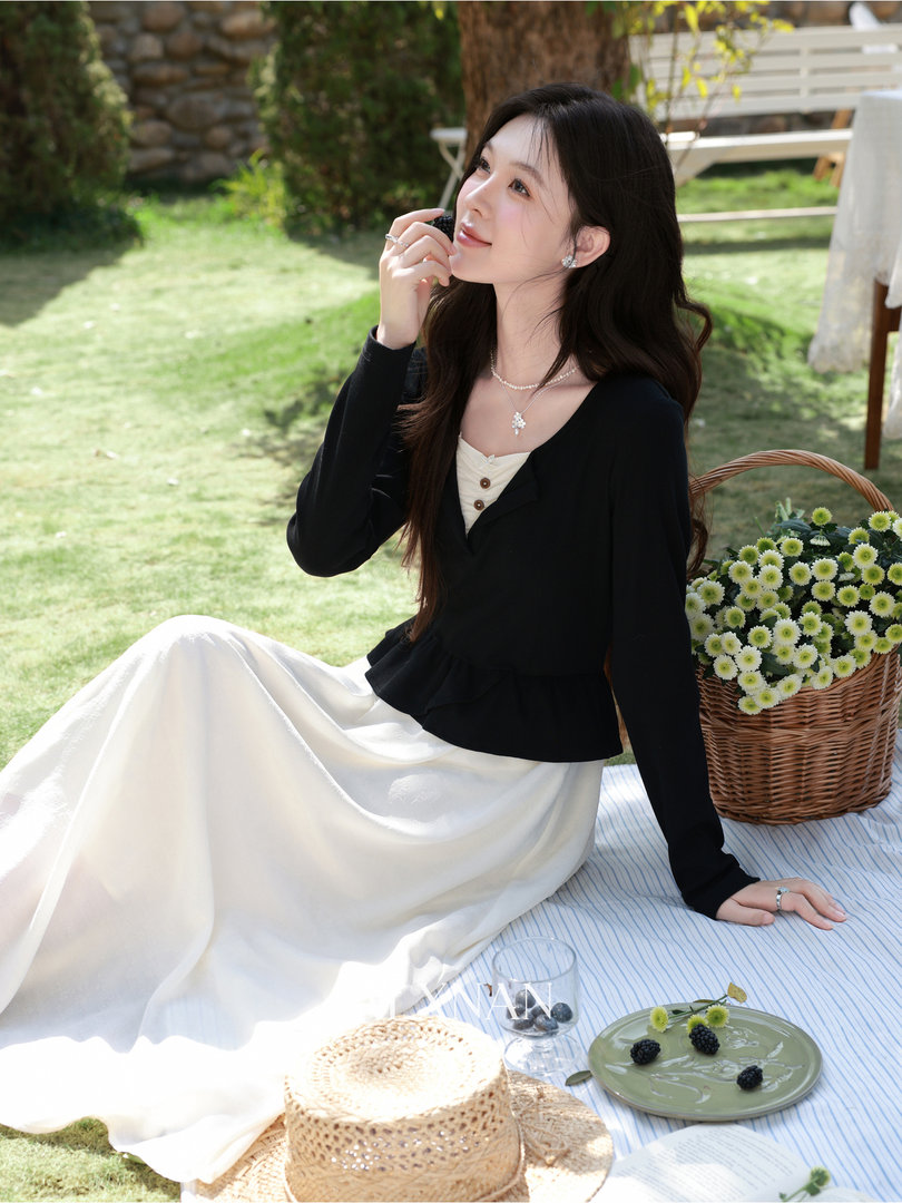Woman wearing a black top and white skirt dress seated at a picnic outdoors
