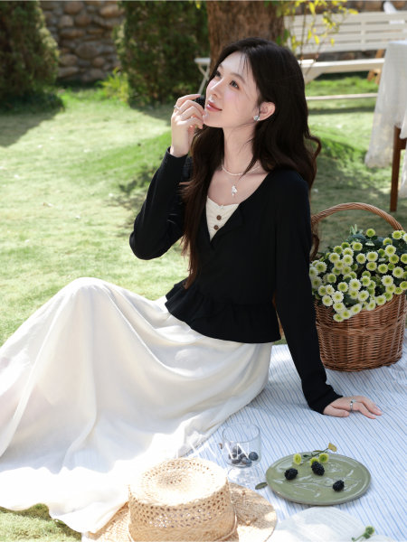 Woman wearing a black top and white skirt dress seated at a picnic outdoors
