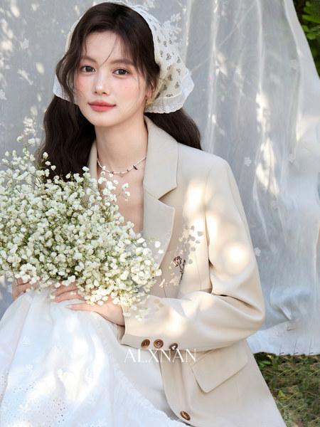 Woman wearing a beige blazer and holding a bouquet of flowers