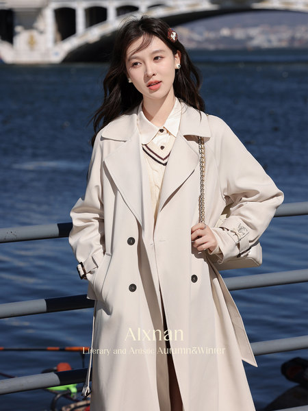 Woman wearing a light beige trench coat outdoors by the water