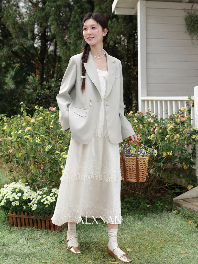Woman wearing a cream blazer over a white midi dress outdoors