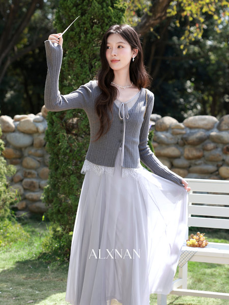 Model wearing a gray ribbed cardigan over a light flowing dress outdoors