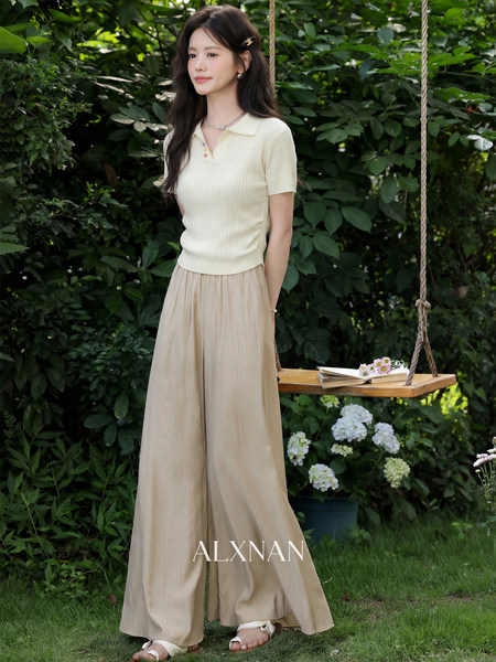 Woman wearing a cream knit polo top and beige wide-leg pants outdoors