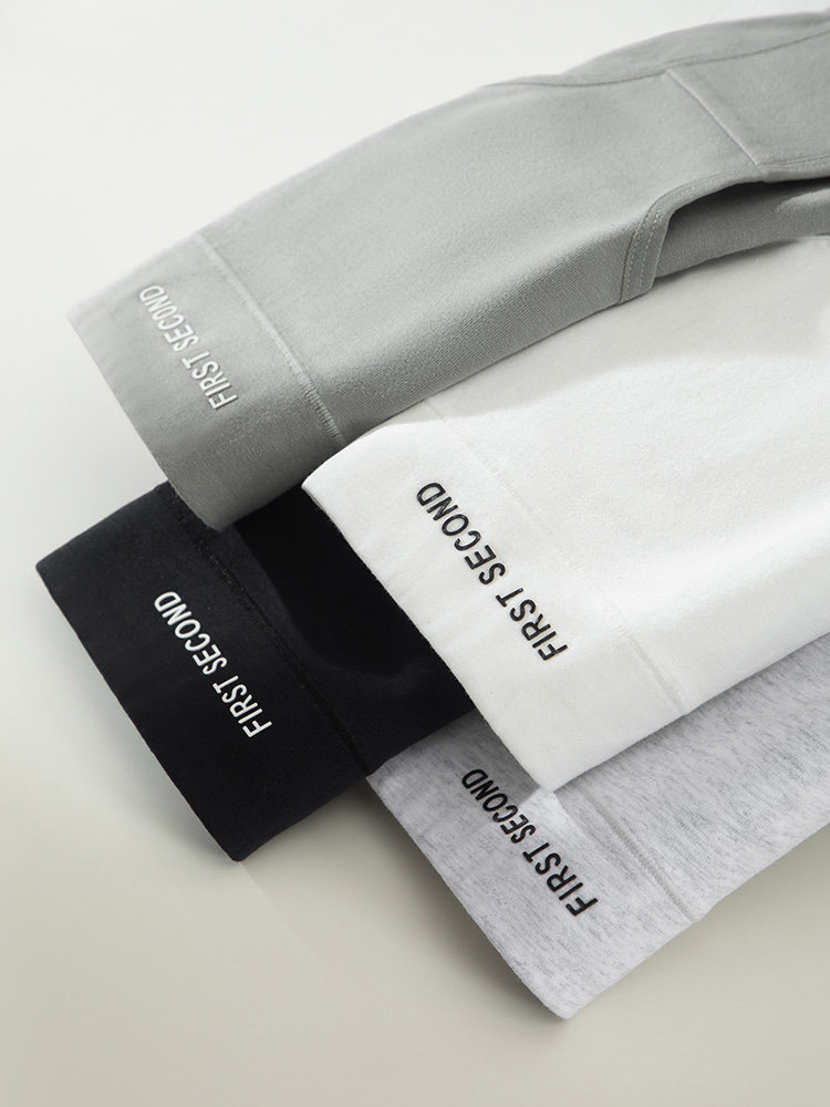 Stacked long-sleeve tops in gray, black, white, and heather gray with printed cuff text