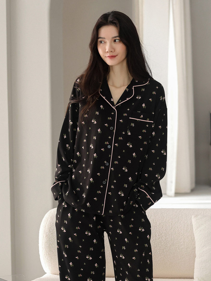 Woman wearing a black floral pajama set with pink piping