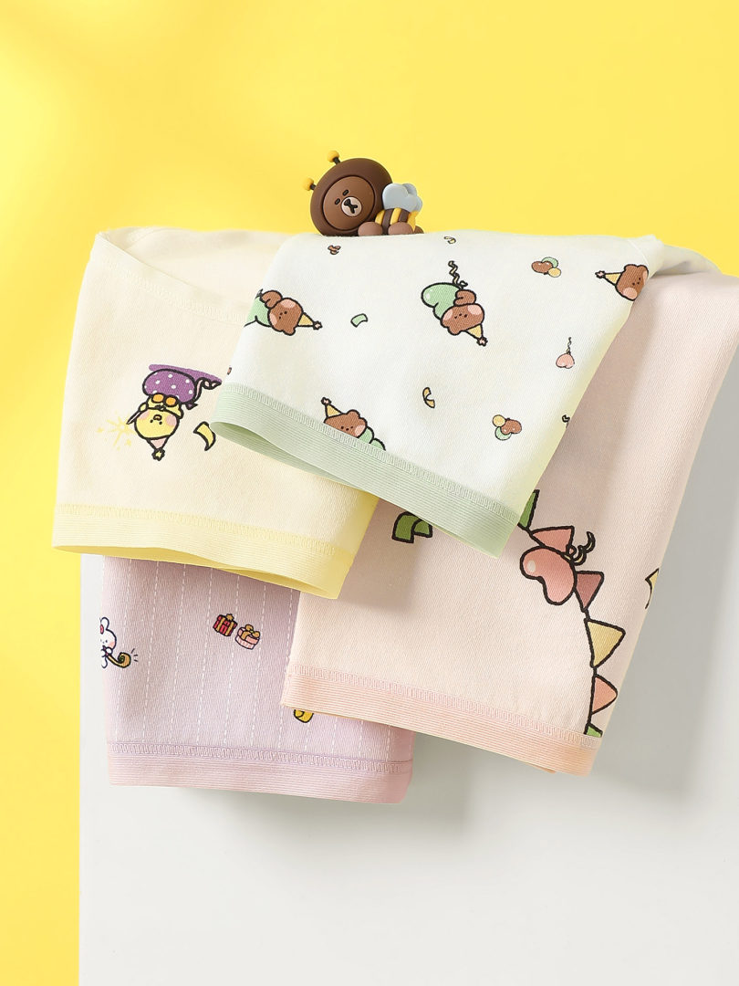 Set of pastel cartoon-print underwear displayed on a yellow background