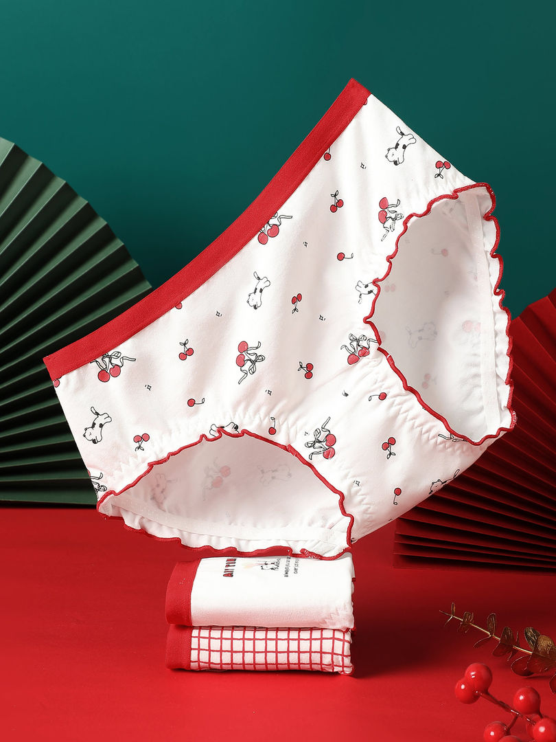 White cherry-print women’s underwear briefs with red trim, displayed flat on a red background
