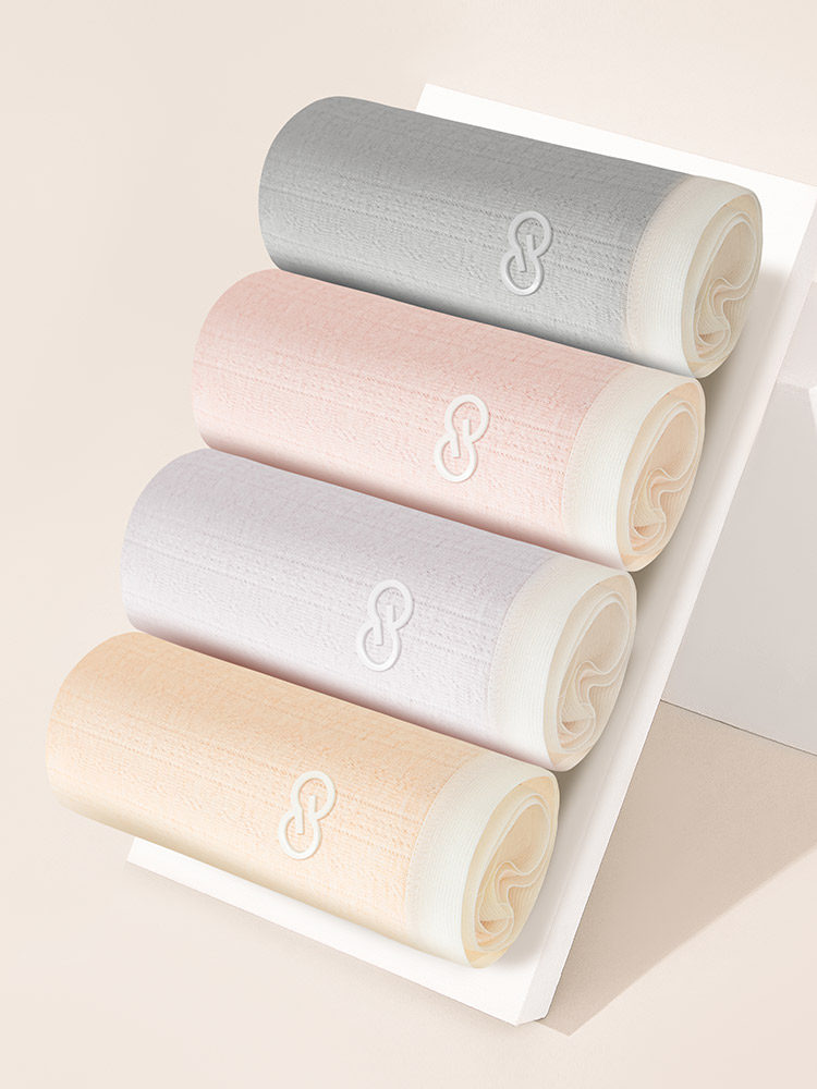 Four rolled pastel fabric garments displayed on a white board