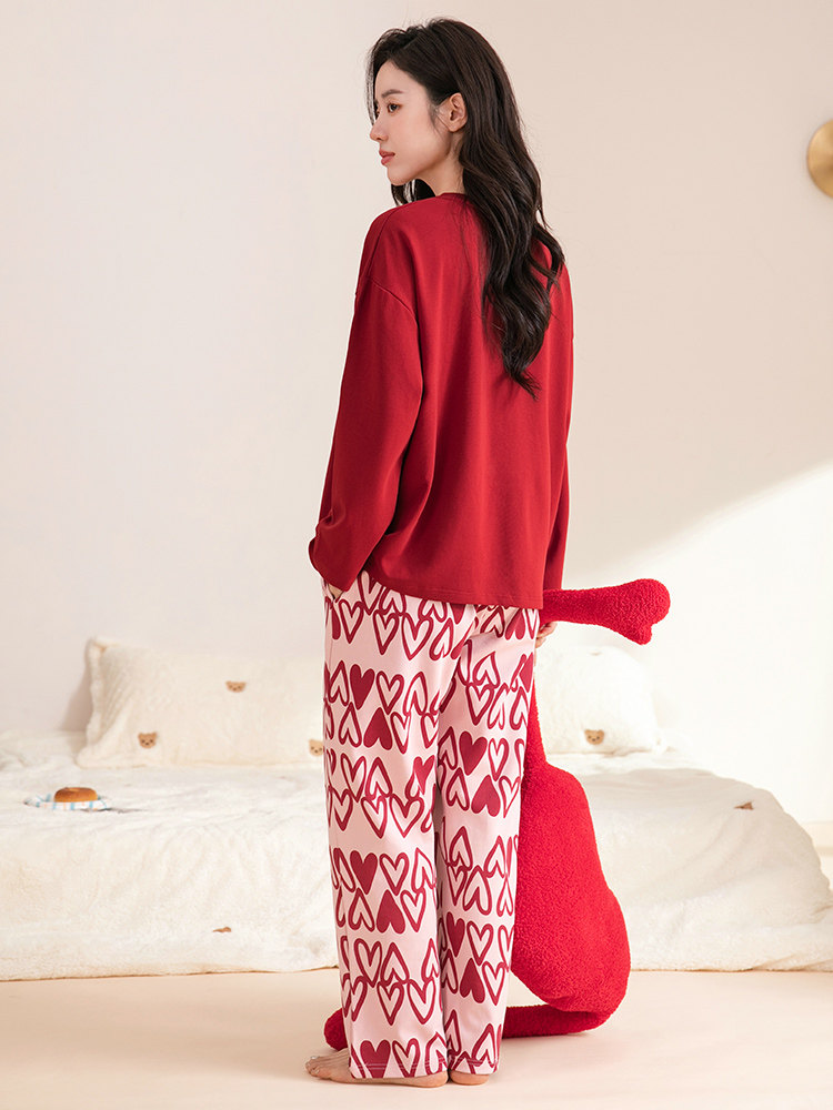 Woman wearing a red sweatshirt and heart-patterned pajama pants