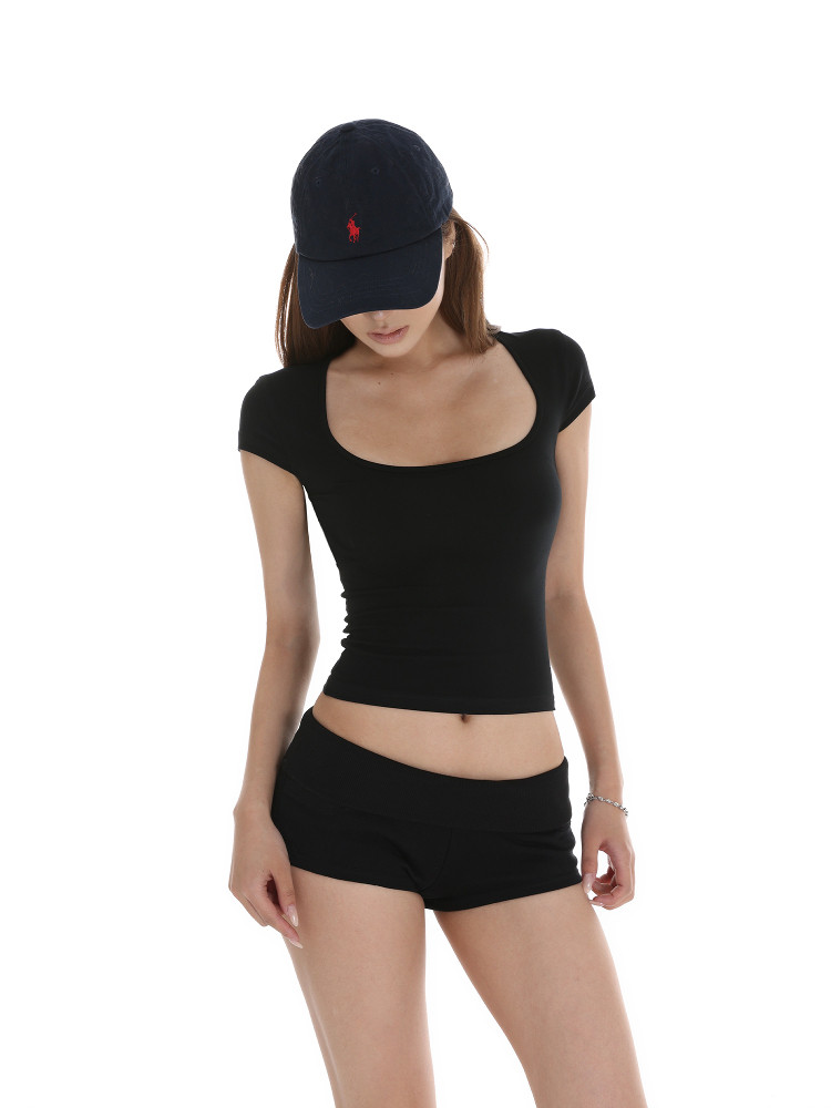 Black fitted crop top and shorts worn with a navy baseball cap on a model