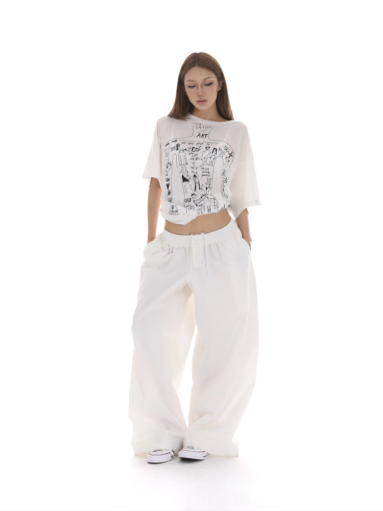 Model wearing a white graphic crop top and loose white pants