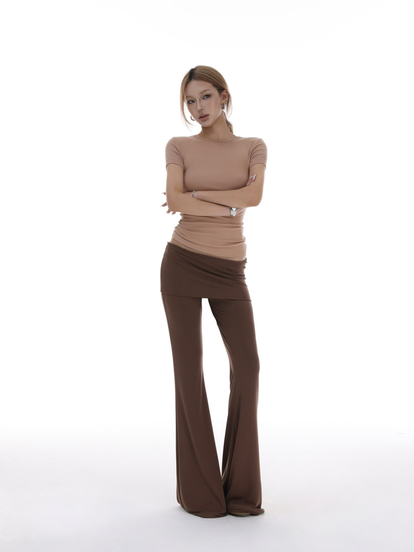 Model wearing a beige fitted short-sleeve top with brown flared pants on a white background