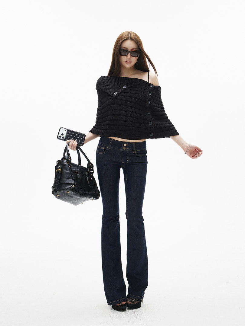 Model wearing a black off-shoulder sweater with dark flared jeans and a black handbag