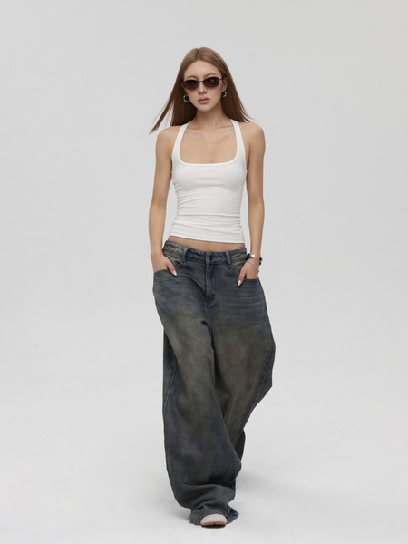 Model wearing a white tank top with oversized dark jeans