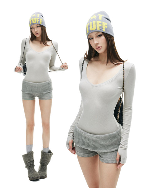Model wearing a gray knit winter outfit with beanie, fitted top, shorts, and leg warmers