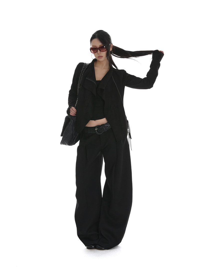 Model wearing an all-black tailored outfit with wide-leg pants, blazer, sunglasses, and a shoulder bag