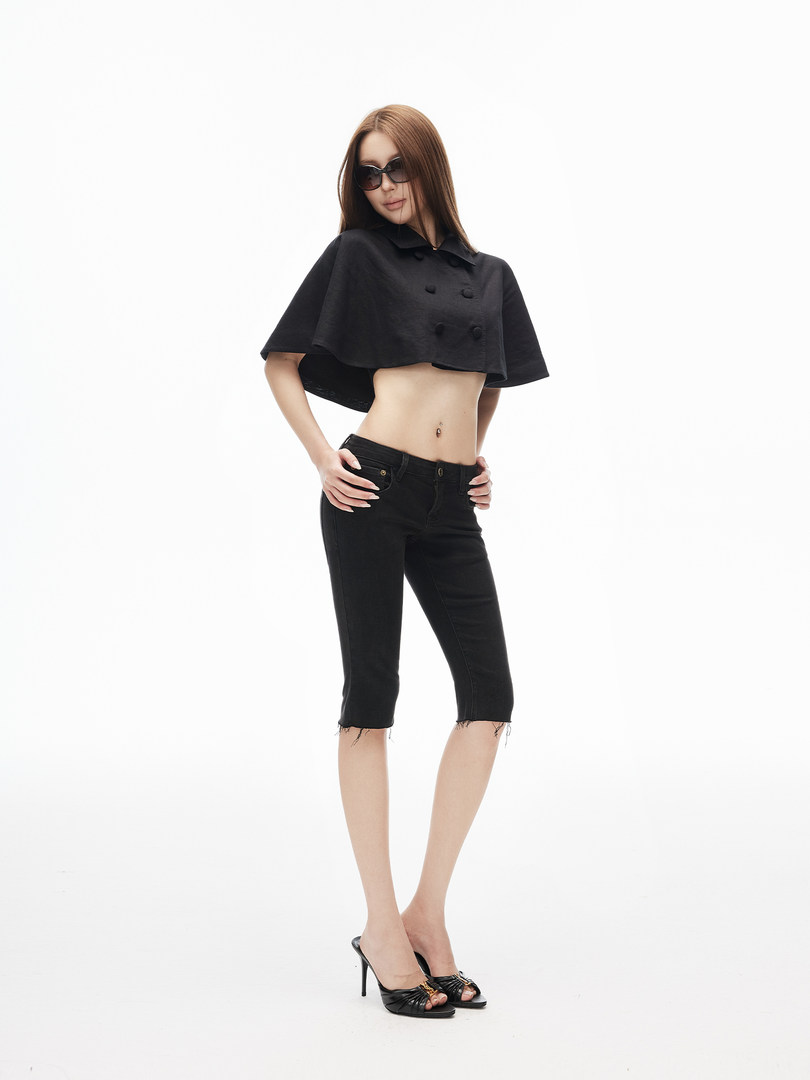 Model wearing a black cropped cape top with black capri jeans and high-heel sandals