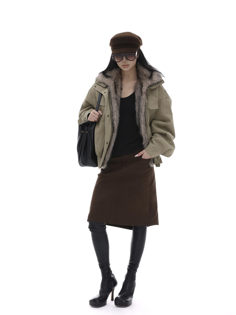 Fashion model wearing a fur-lined jacket, skirt, leggings, and black heeled boots with a handbag