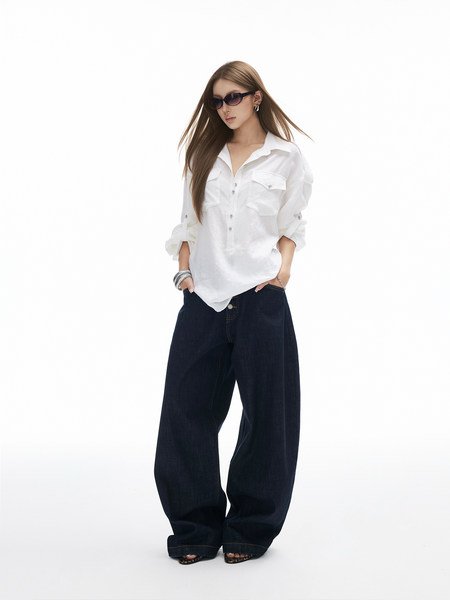 Model wearing a white button-up shirt and dark wide-leg jeans