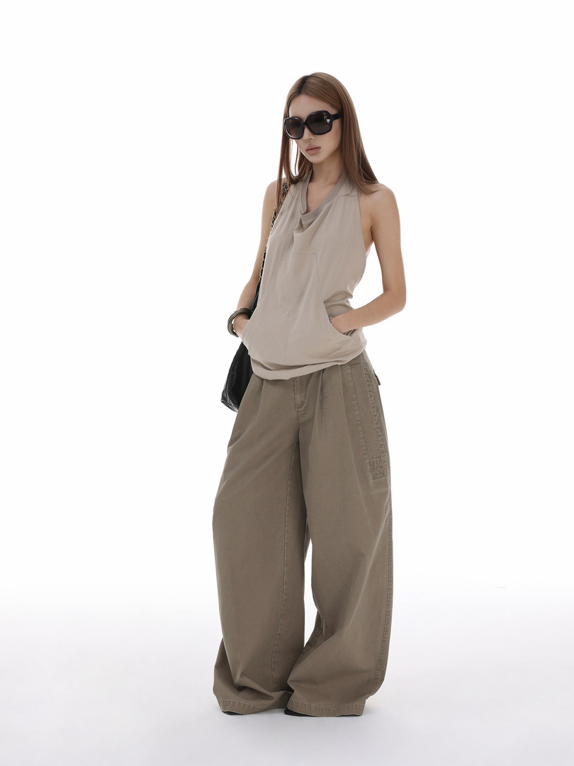 Model wearing a sleeveless beige top and loose brown wide-leg pants with sunglasses