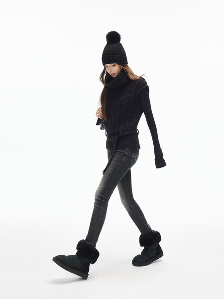 Model wearing black winter outfit with beanie, sweater, jeans, and fur-trim boots