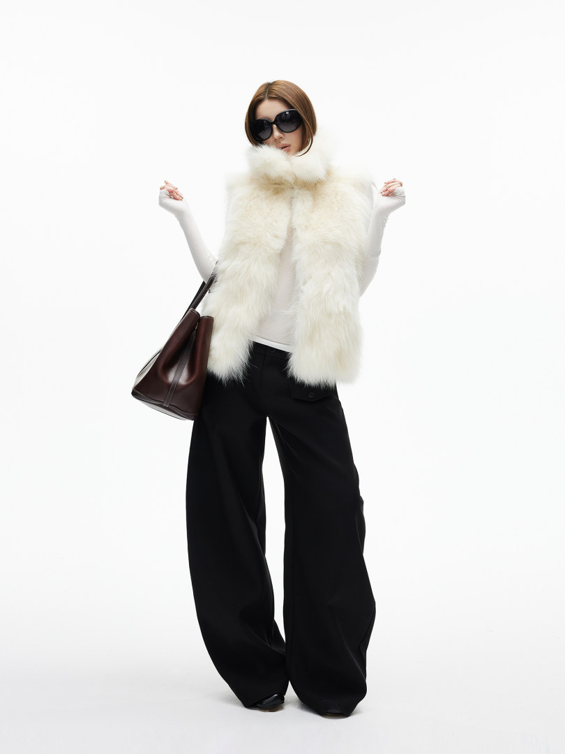 Model wearing a white fur vest with black wide-leg pants and sunglasses