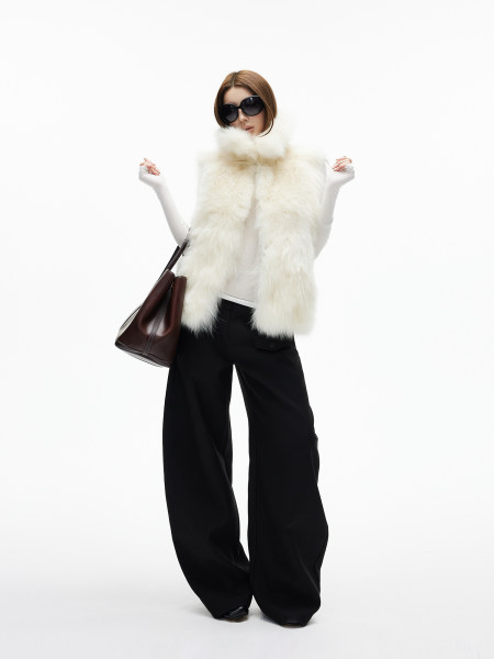 Model wearing a white fur vest with black wide-leg pants and sunglasses