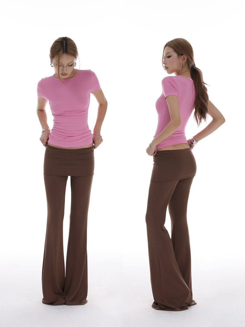 Model wearing a pink fitted top with brown flared pants and layered mini skirt detail