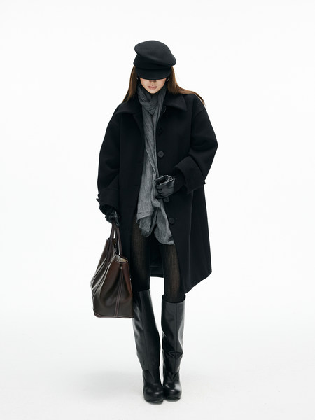 Fashion model wearing a black coat, hat, gloves, boots, and carrying a leather tote bag