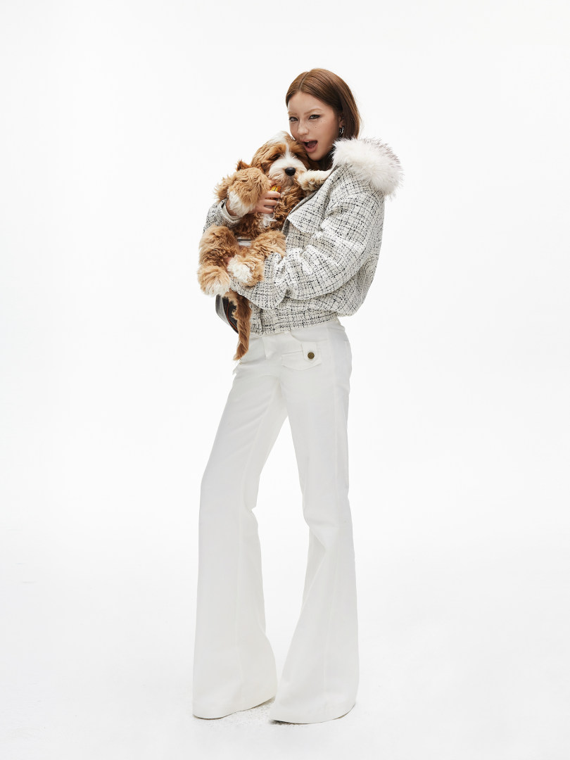 Fashion model wearing a white tweed jacket with fur collar and white flared pants
