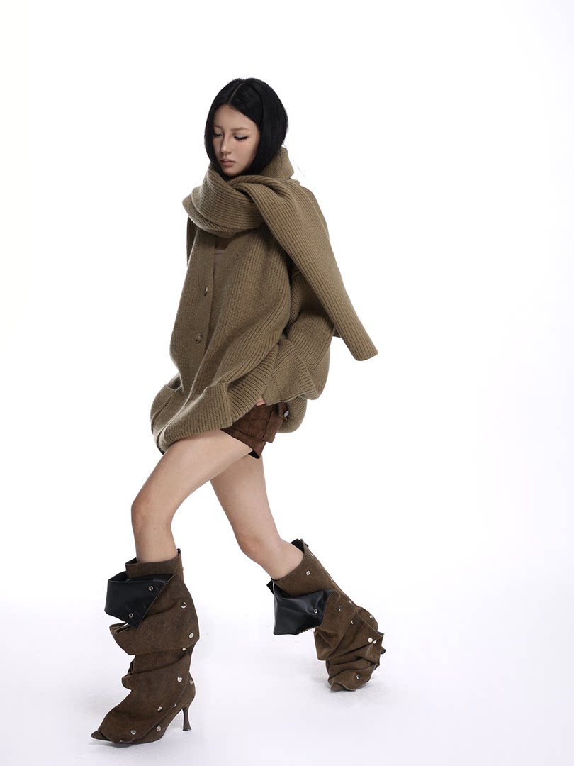 Model wearing an oversized knit sweater, scarf, and slouchy brown boots