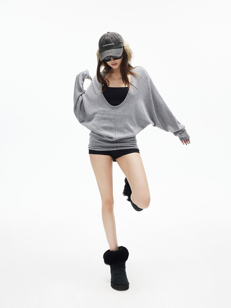 Model wearing an oversized gray sweatshirt with black shorts, cap, and fur-trim boots