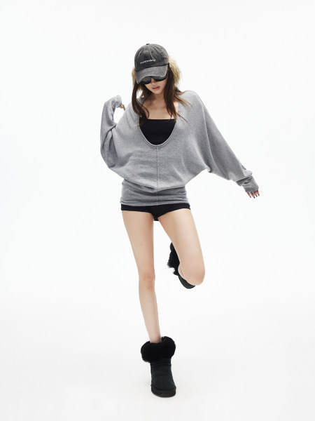 Model wearing an oversized gray sweatshirt with black shorts, cap, and fur-trim boots