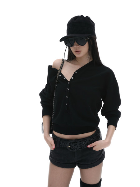 Model wearing a black off-shoulder top, shorts, hat, and sunglasses on a white background