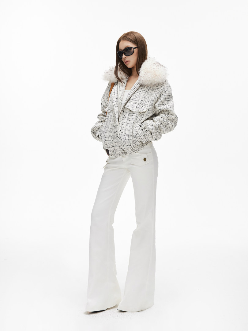 Model wearing a white tweed winter jacket with fur collar and white flared pants