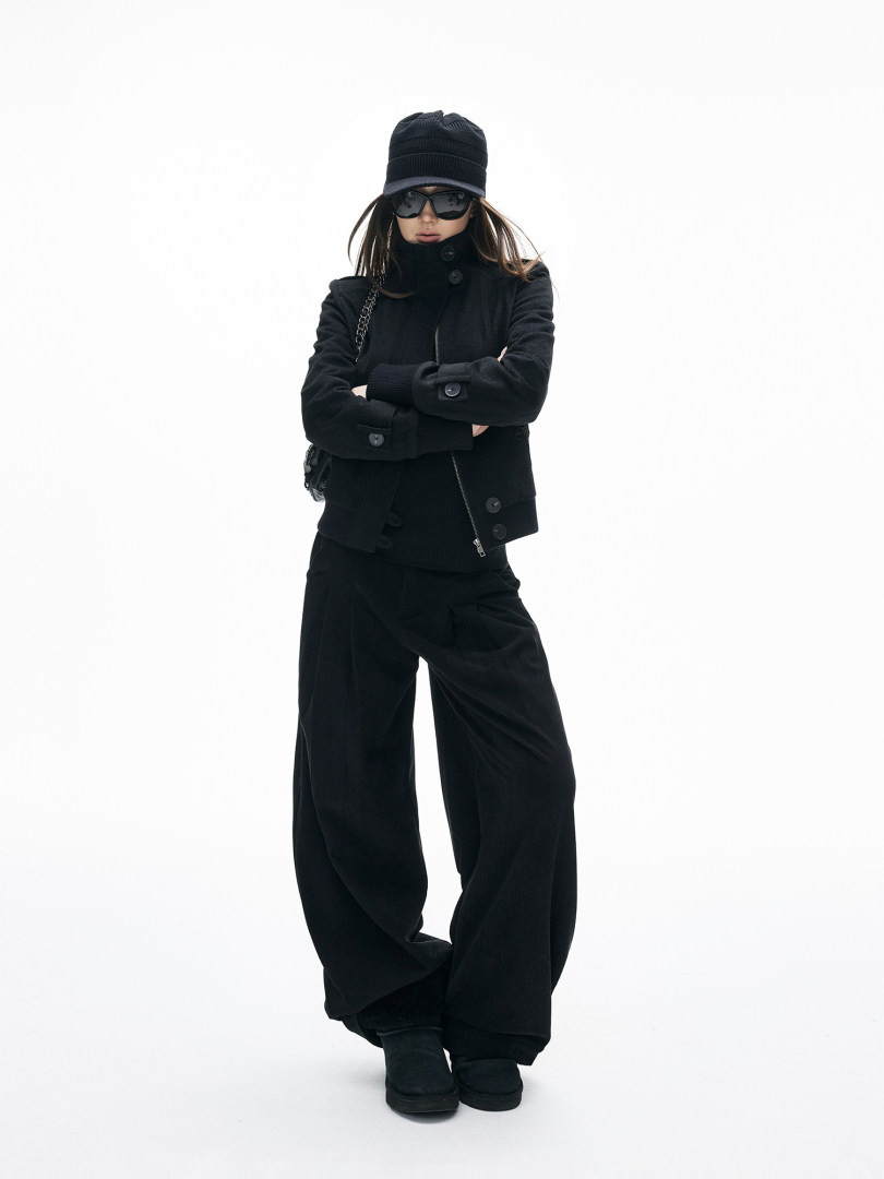 Model wearing an all-black winter outfit with hat, sunglasses, jacket, and wide-leg pants