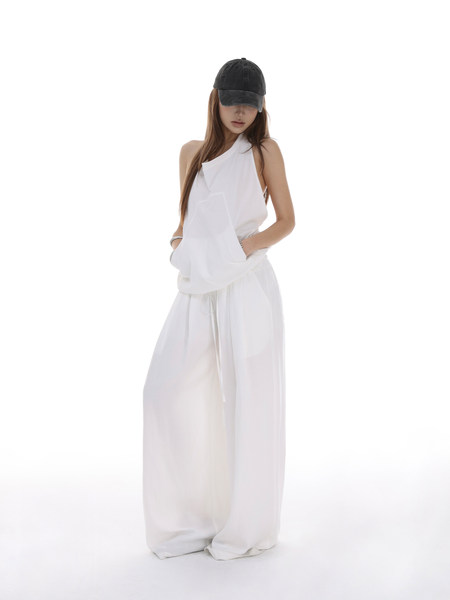 Model wearing a white wide-leg outfit with a black cap on a white background
