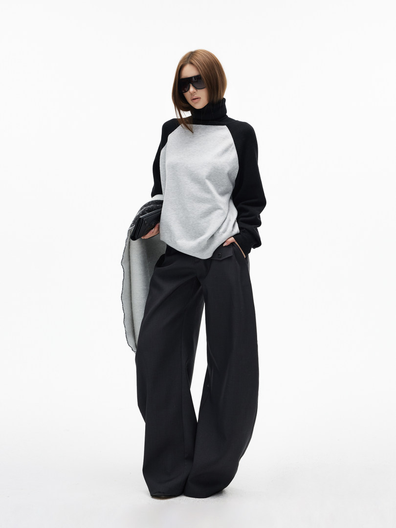 Fashion model wearing a black and gray turtleneck top with wide-leg black pants