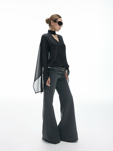 Model wearing a black sheer blouse with wide-leg trousers