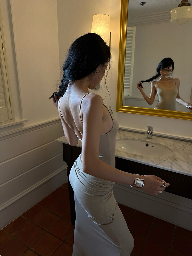 Woman wearing a light gray fitted sleeveless dress in a mirror selfie