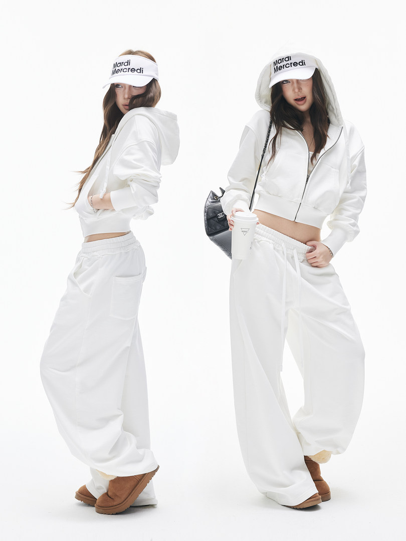 Two models wearing a white hooded tracksuit with wide-leg pants and visor hats