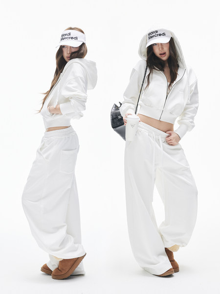 Two models wearing a white hooded tracksuit with wide-leg pants and visor hats