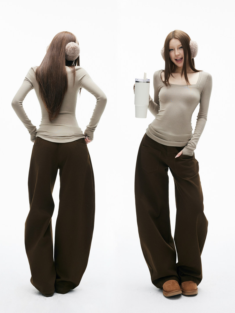 Model wearing a beige fitted long-sleeve top and dark wide-leg pants with earmuffs