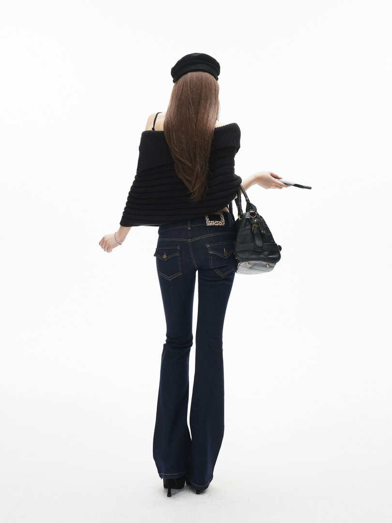 Model wearing a black off-shoulder top with flared dark jeans and a black handbag