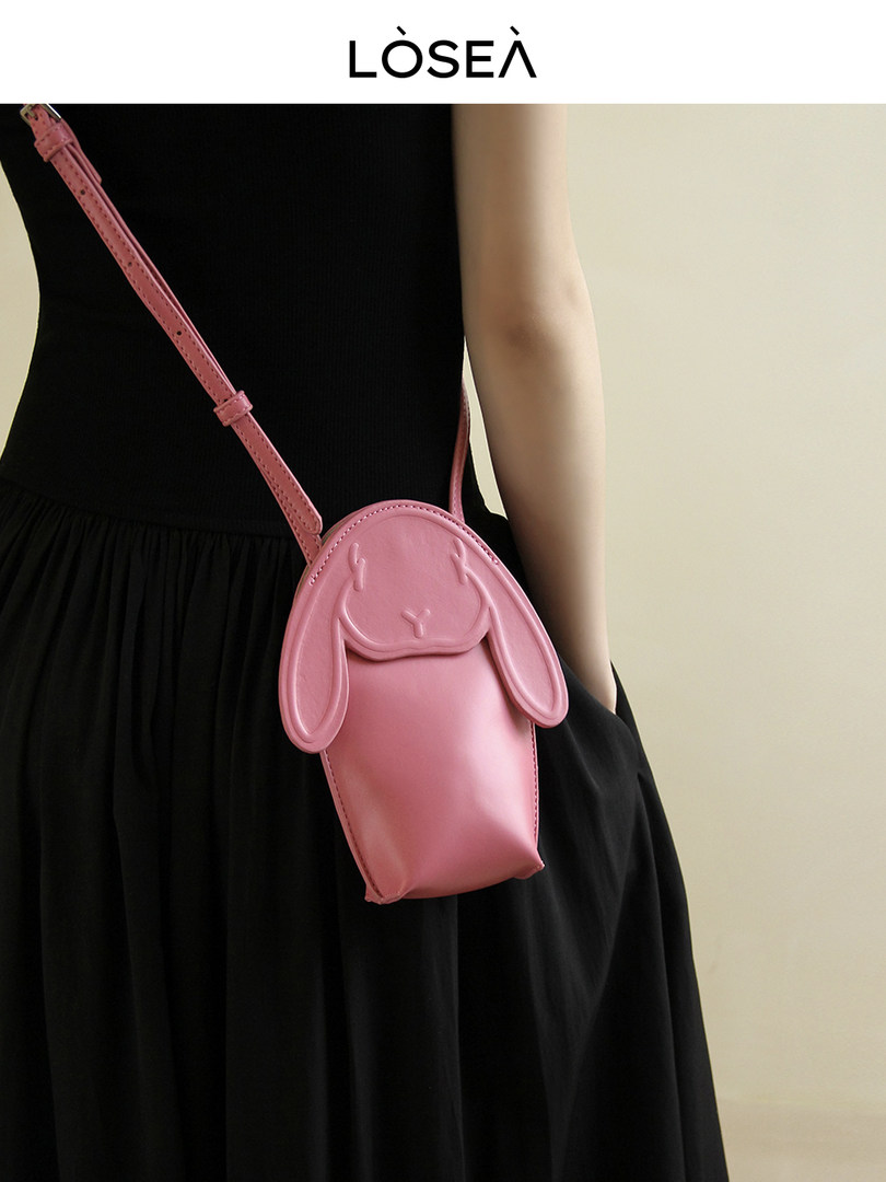 Pink rabbit-shaped crossbody bag worn with a black dress