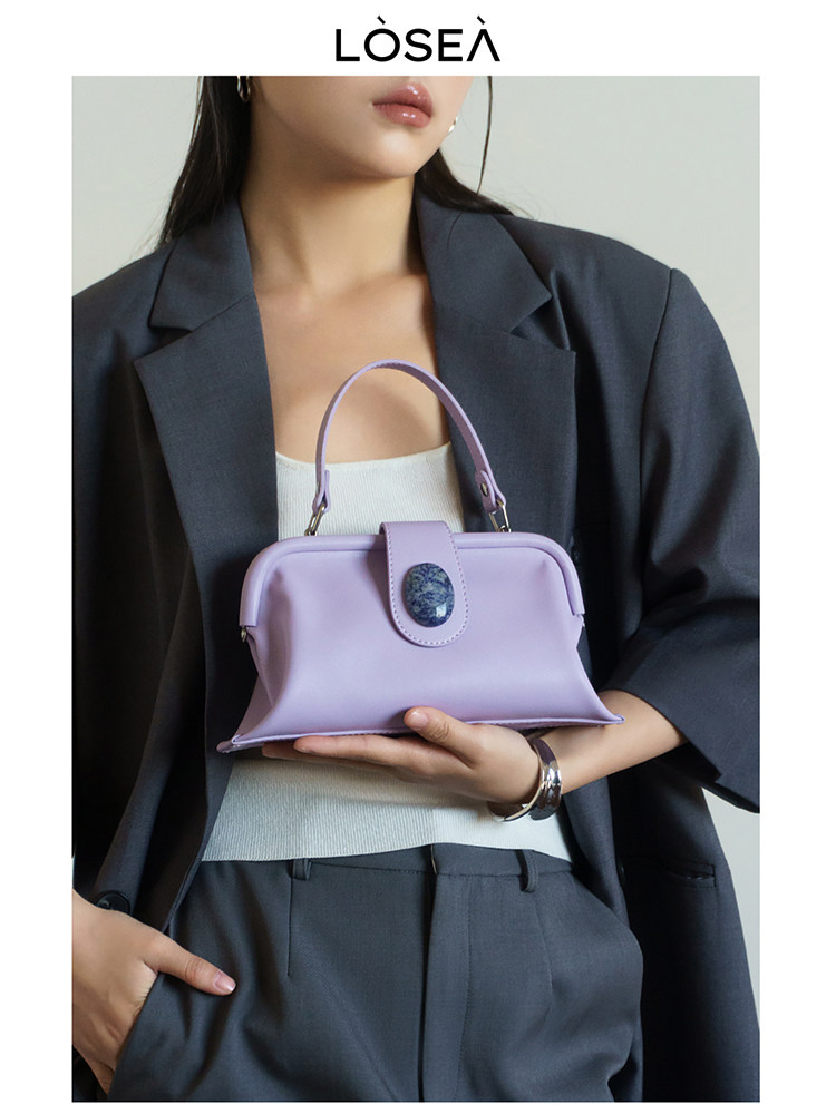 Lavender handbag held by a model wearing a dark blazer