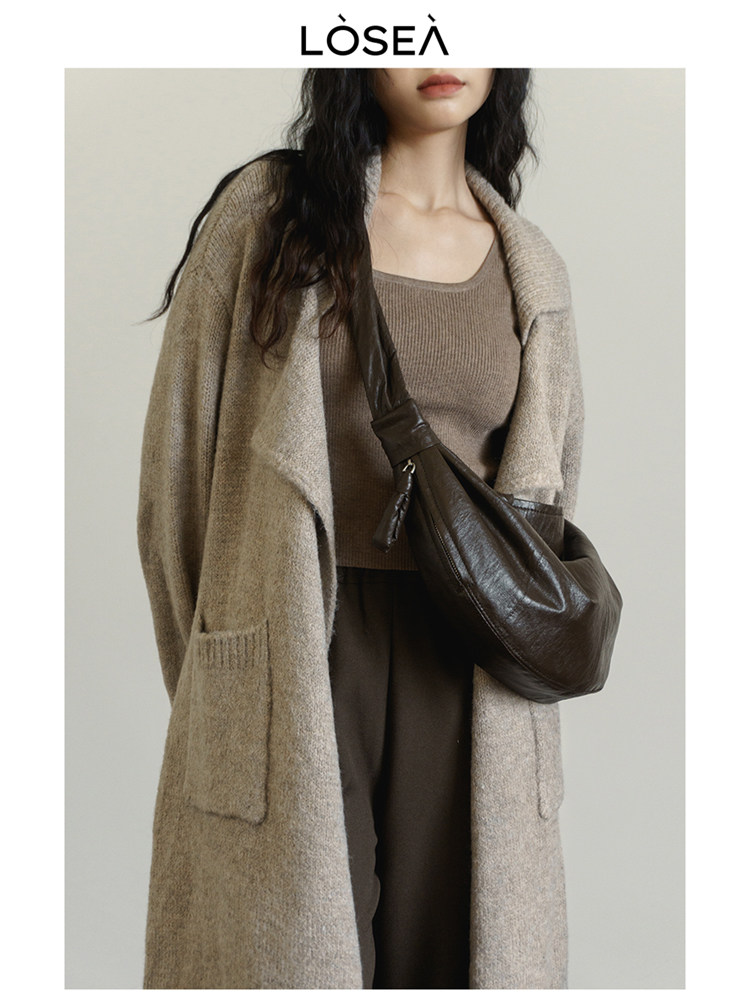 Model wearing a beige long knit coat with a brown top and crossbody bag