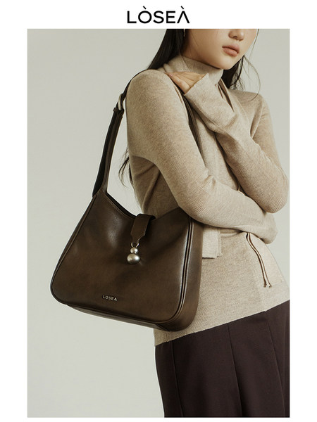 Brown leather shoulder bag worn by a model