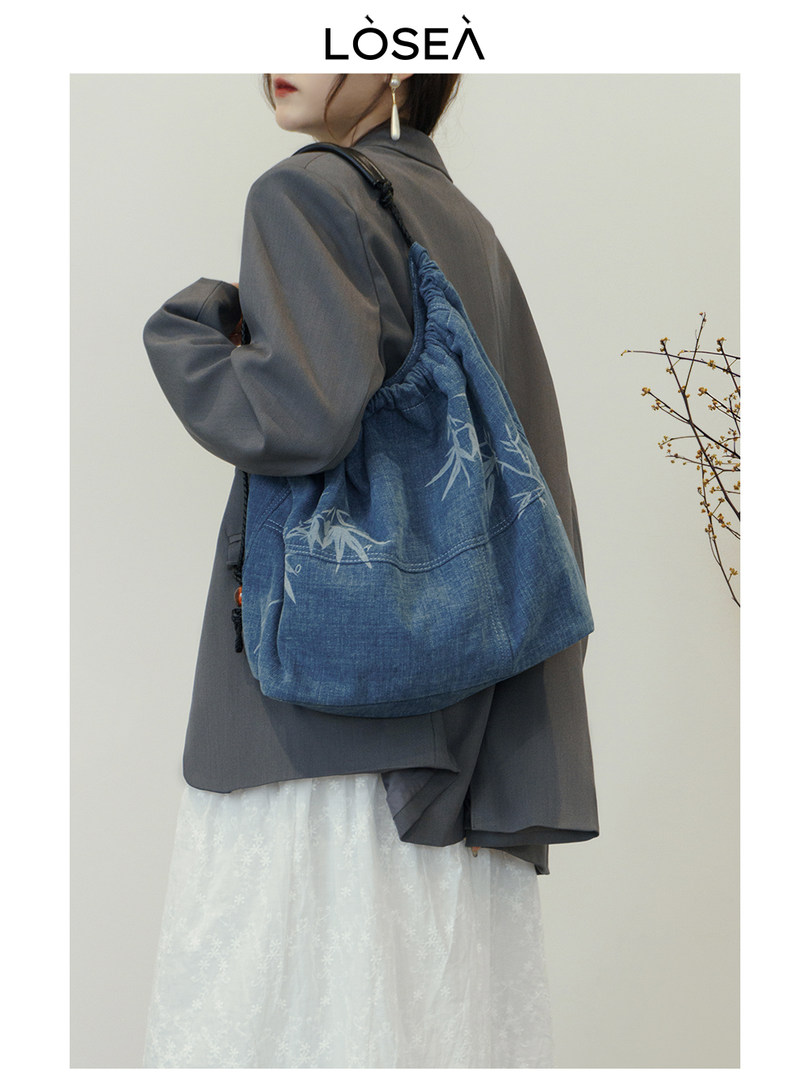 Model wearing a blue denim drawstring shoulder bag