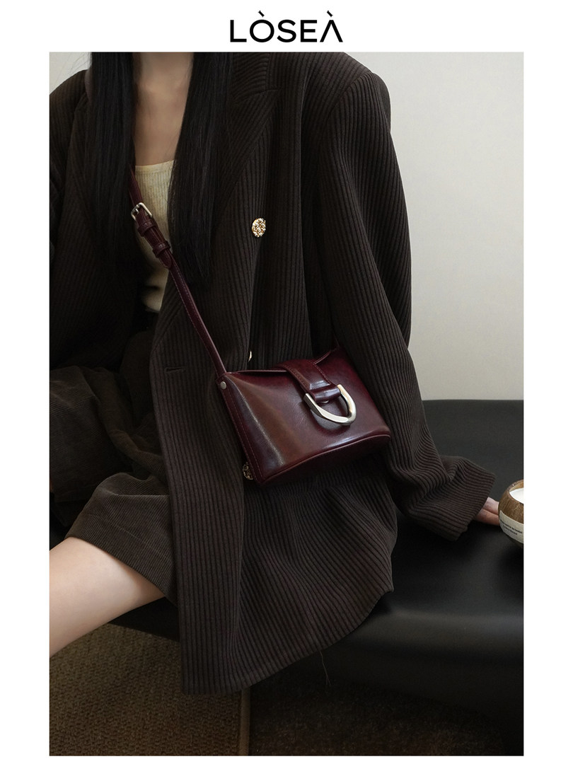 Woman wearing a burgundy leather crossbody bag with a dark ribbed outfit